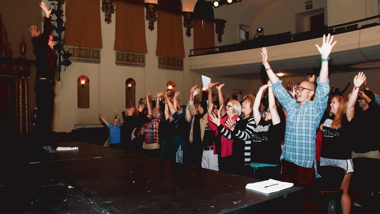 Students standing up with their hands in the air