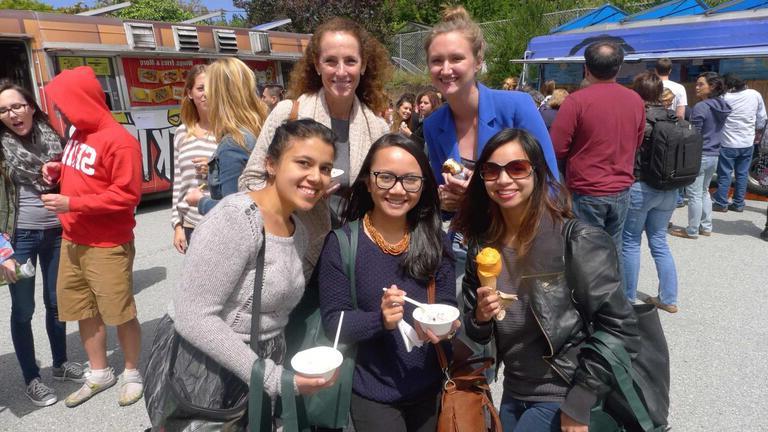 Five students posing for picture holding takeout containers of food