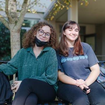 Two students sit on a bench.