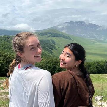 Two students sit on a hill looking over a valley