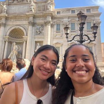 Two students pose in front of an ancient Roman building.